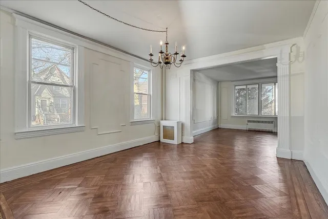 a view of an empty room with window and wooden floor