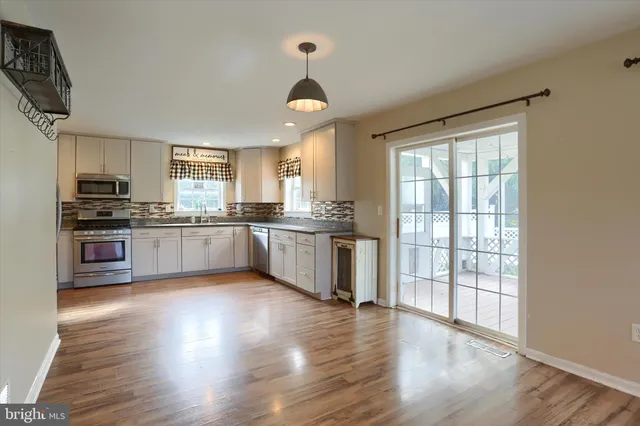 a kitchen with stainless steel appliances granite countertop wooden floors and white cabinets