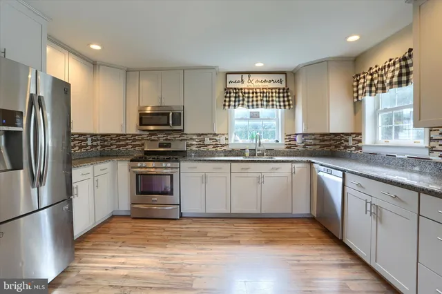a kitchen with granite countertop a stove a sink and a refrigerator