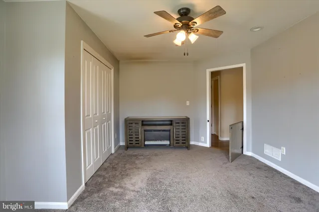 an empty room with a ceiling fan and a window