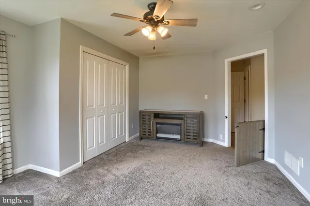 a view of empty room with fireplace and fan