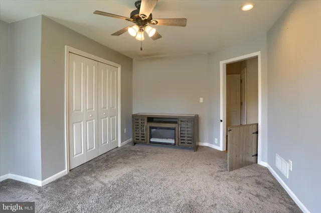 a view of empty room with fireplace and fan