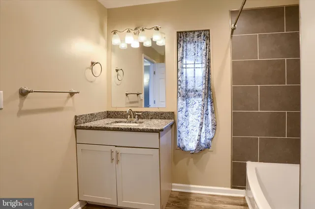 a bathroom with a granite countertop sink a toilet and shower