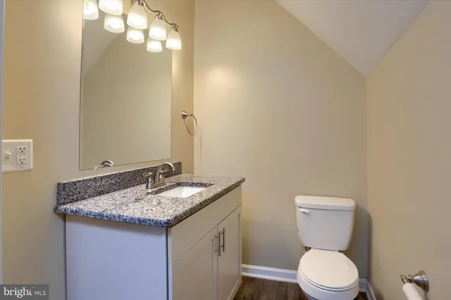 a bathroom with a granite countertop toilet sink and mirror
