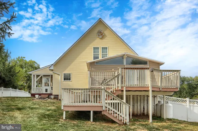 a view of a house with a wooden deck and a lake view