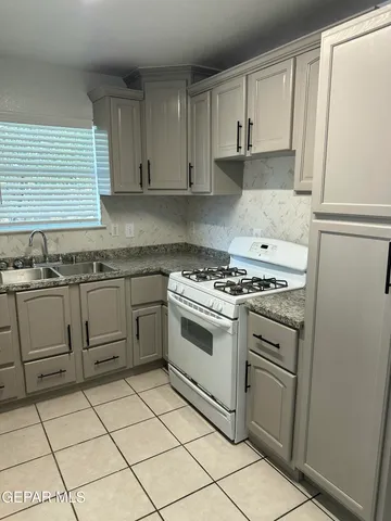a kitchen with white cabinets appliances and a window