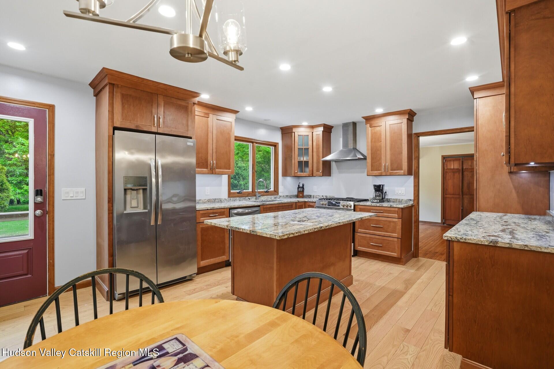 984 Blue Mountain Road Saugerties, NY 12477 - Photo 11 of 24 a kitchen with stainless steel appliances granite countertop a refrigerator a stove a sink a dining table and chairs with wooden floor