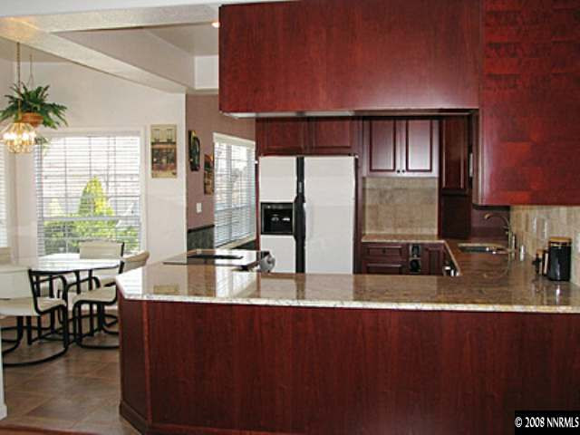 35 Telluride Court Reno, NV 89511 - Photo 6 of 8 a kitchen with stainless steel appliances granite countertop a refrigerator a stove and a sink with wooden cabinets