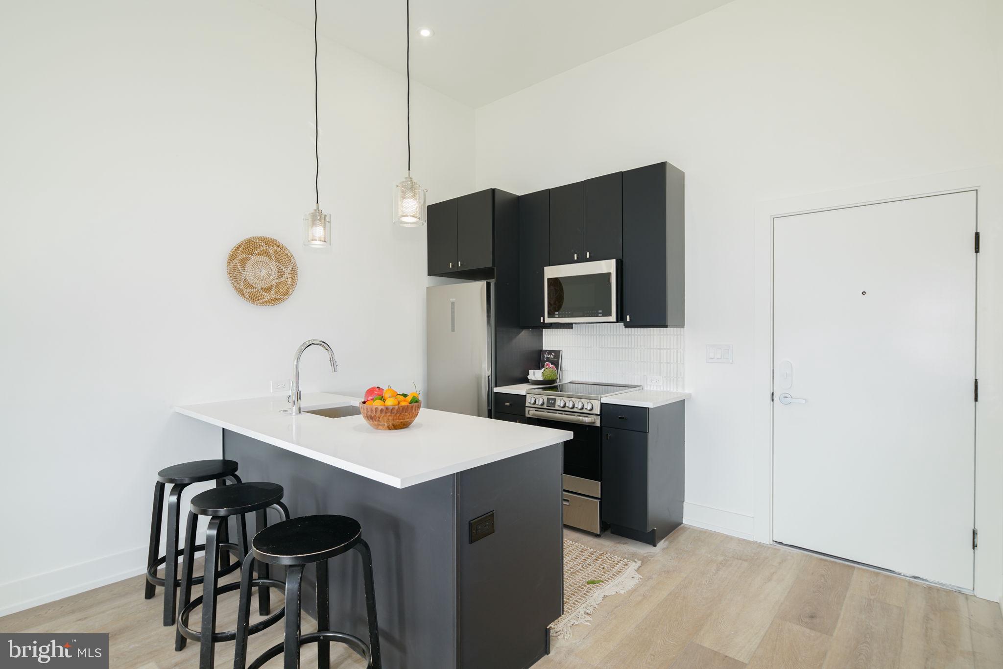 5013 Springfield Avenue, Unit 515 Philadelphia, PA 19143 - Photo 7 of 21 a kitchen with a sink a stove a refrigerator with a dining table and chairs