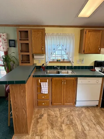 a kitchen with granite countertop a sink a stove and a wooden cabinets