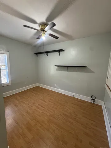 an empty room with a ceiling fan and window