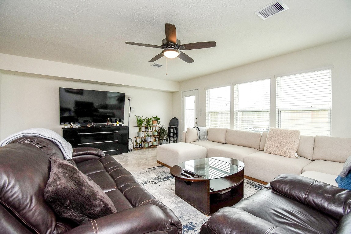 5912 Whitewing Road Rosenberg, TX 77469 - Photo 11 of 25 Spacious and inviting living room featuring ample natural light, stylish ceiling fan, and a cozy seating area perfect for relaxation and entertainment.