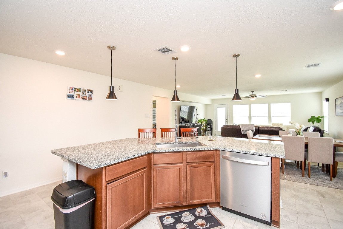 5912 Whitewing Road Rosenberg, TX 77469 - Photo 14 of 25 Elegant kitchen with sleek granite countertops and rich wooden cabinets, seamlessly connected to a spacious, light-filled living area. Perfect for entertaining.