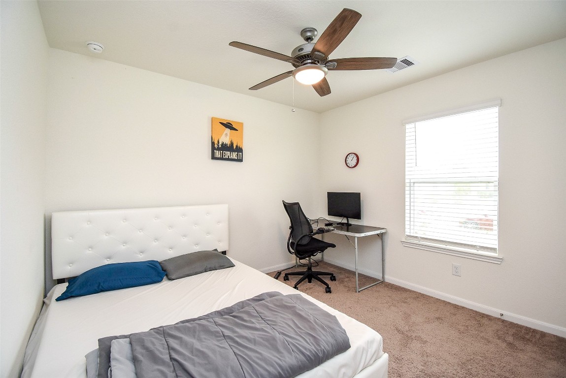 5912 Whitewing Road Rosenberg, TX 77469 - Photo 21 of 25 This bright bedroom offers a cozy atmosphere with soft carpeting, a stylish ceiling fan, and ample natural light. Perfect for relaxation or a productive workspace.