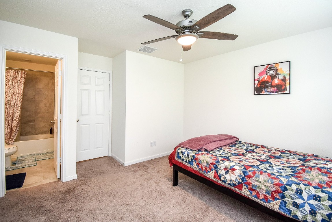 5912 Whitewing Road Rosenberg, TX 77469 - Photo 23 of 25 Cozy bedroom with plush carpeting, a ceiling fan, and an en-suite bathroom.