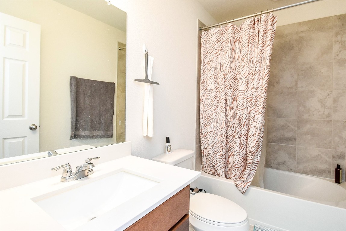 5912 Whitewing Road Rosenberg, TX 77469 - Photo 24 of 25 Modern bathroom featuring a sleek vanity, elegant tilework, and a stylish shower curtain, offering both comfort and functionality.