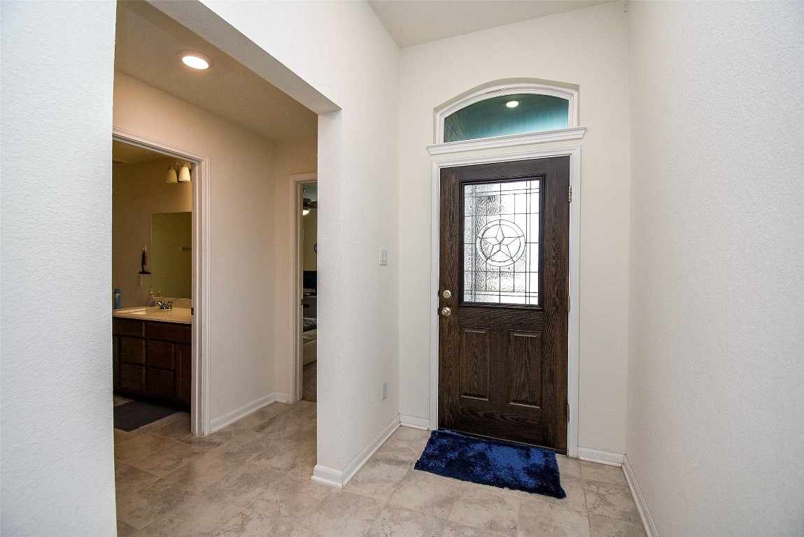 5912 Whitewing Road Rosenberg, TX 77469 - Photo 8 of 25 Welcome home to this inviting entrance, featuring a stylish wooden door and elegant tile flooring, setting the tone for a warm and welcoming interior.