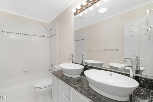 a spacious en suite bathroom with double vanity and a bathtub