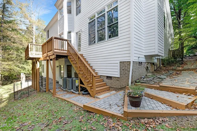 a view of a white house next to a yard with large trees