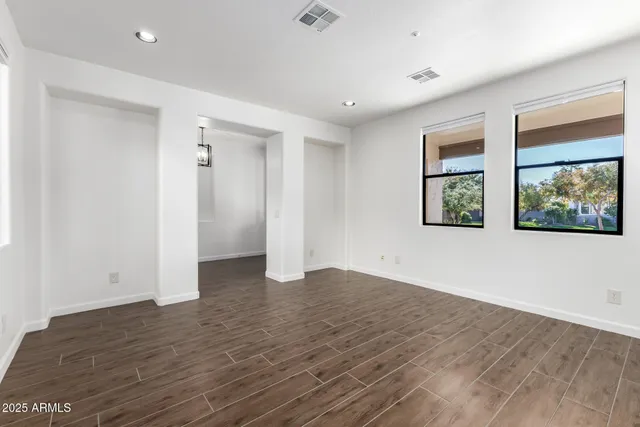 a view of an empty room with window and wooden floor