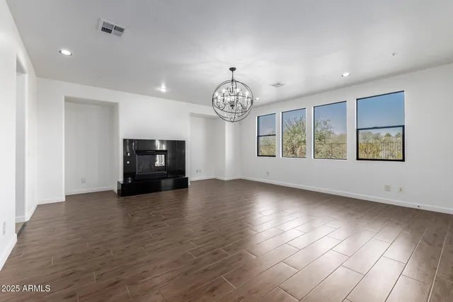 an empty room with wooden floor windows and fireplace