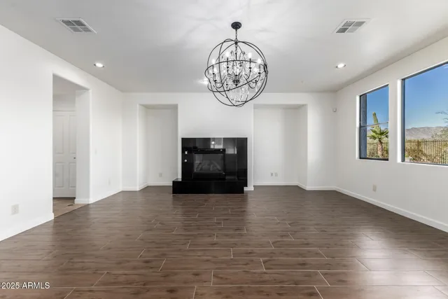a view of an empty room with window and wooden floor