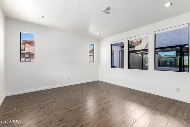 a view of an empty room with wooden floor and window