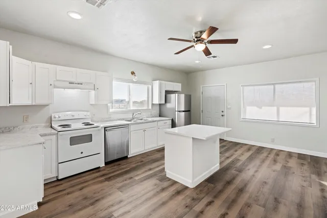 a open kitchen with white cabinets and stainless steel appliances