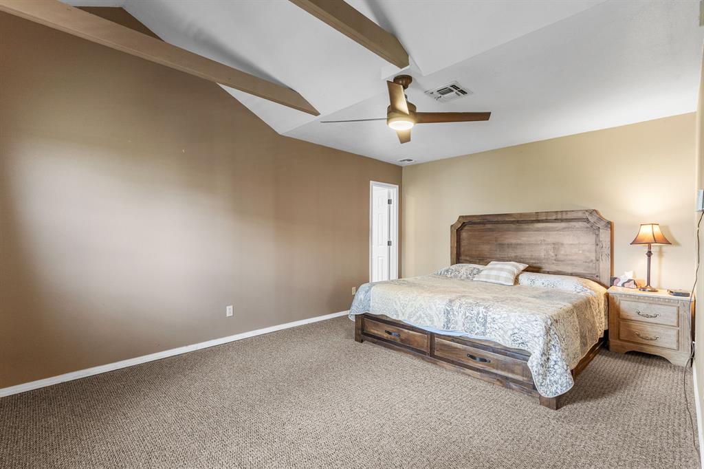 13315 Highway 281 Scotland, TX 76379 - Photo 16 of 40 Vaulted ceiling with exposed wood beams, ceiling fan with integrated lighting, textured carpeting, and a white interior door