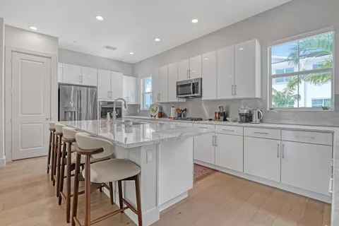a kitchen with kitchen island granite countertop wooden floors white cabinets and stainless steel appliances