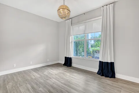 a view of an empty room with a window and hardwood floor
