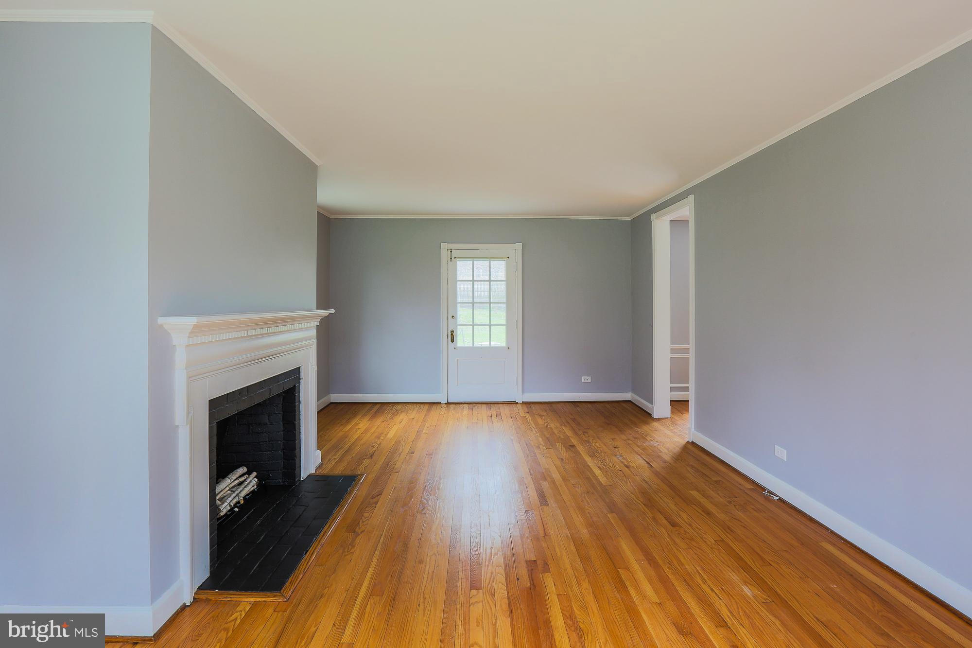 5409 Springlake Way Baltimore, MD 21212 - Photo 14 of 41 an empty room with wooden floor fireplace and windows