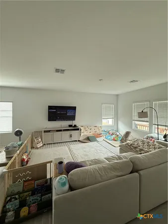 a living room with furniture a flat screen tv and a window