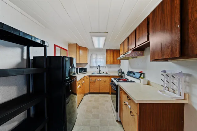 a kitchen that has a sink a refrigerator and a stove top oven