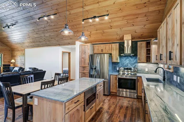 a kitchen with stainless steel appliances kitchen island granite countertop a stove a refrigerator and a dining table