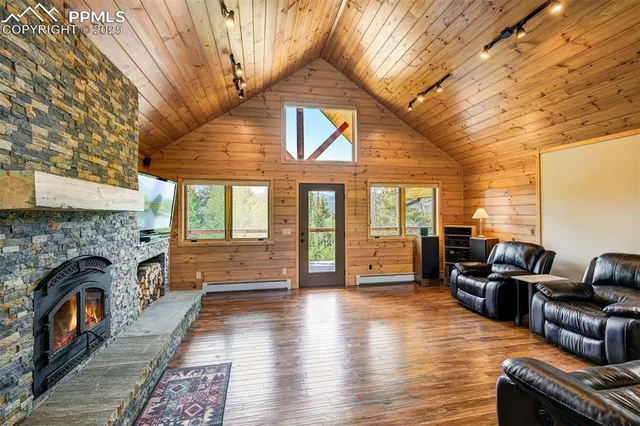 a view of a livingroom with furniture wooden floor fireplace and windows