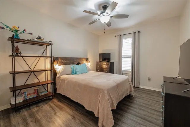 a bedroom with a bed a dresser with wooden floor
