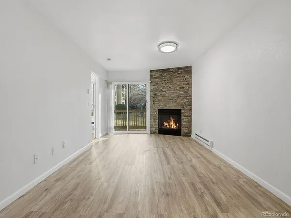 an empty room with wooden floor fireplace and windows