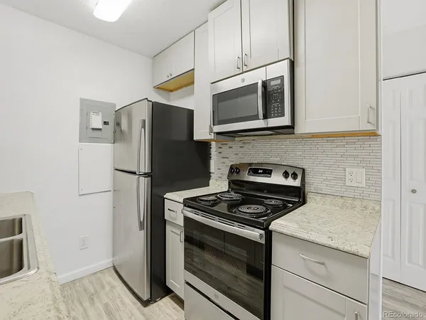 a kitchen with stainless steel appliances white cabinets and a stove a refrigerator with wooden floor