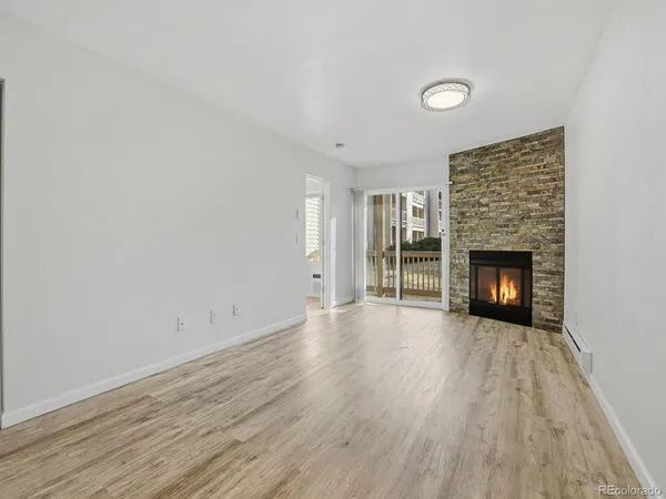 an empty room with wooden floor fireplace and windows
