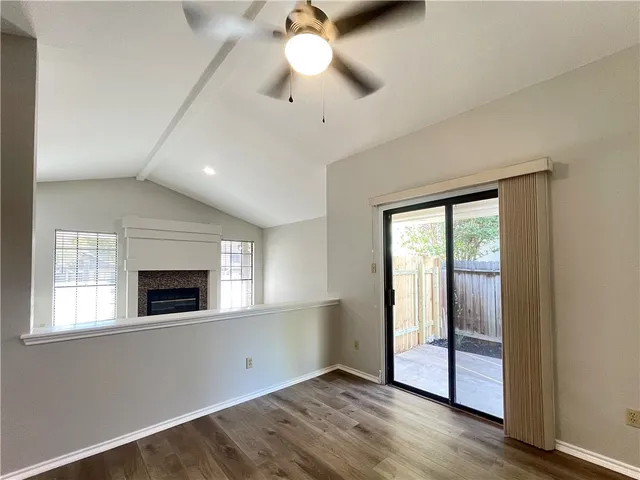 a view of an empty room with window and wooden floor