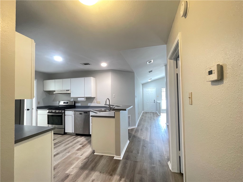 12333 Yarmont Way Austin, TX 78753 - Photo 23 of 40 a kitchen with stainless steel appliances granite countertop a stove top oven a sink dishwasher a refrigerator and cabinets with wooden floor
