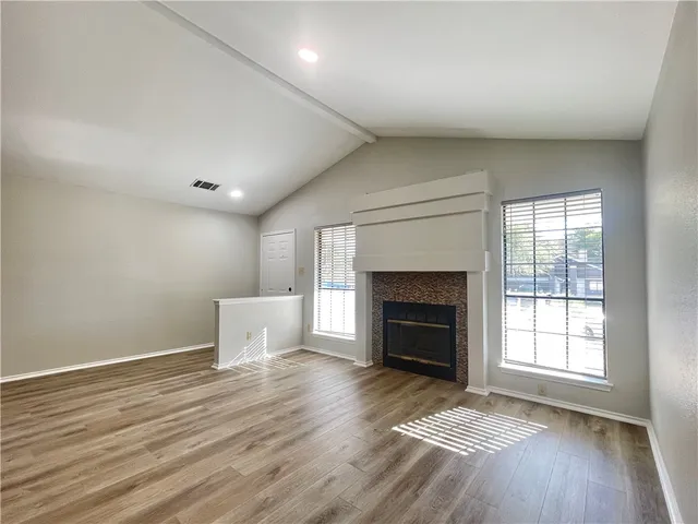 an empty room with windows and fireplace