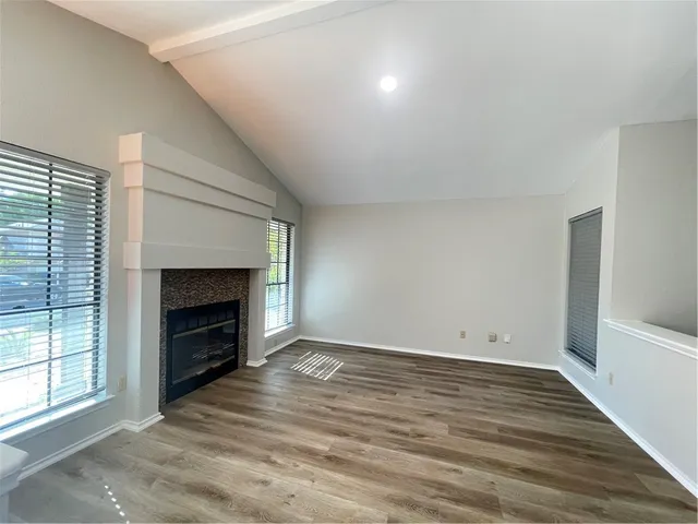 a view of empty room with wooden floor and fireplace