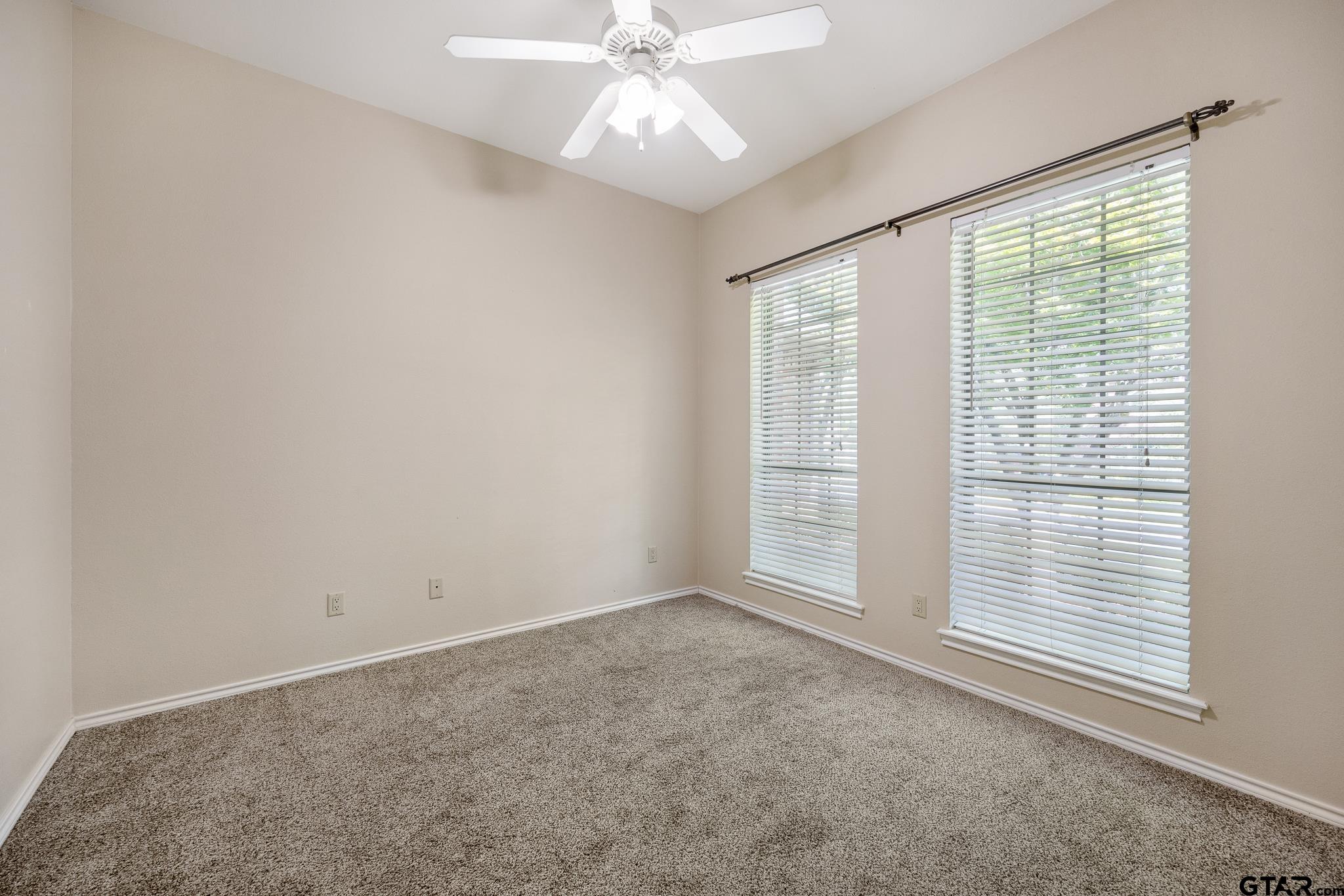 5603 Thomas Nelson Drive Tyler, TX 75707 - Photo 18 of 28 an empty room with chandelier fan and windows