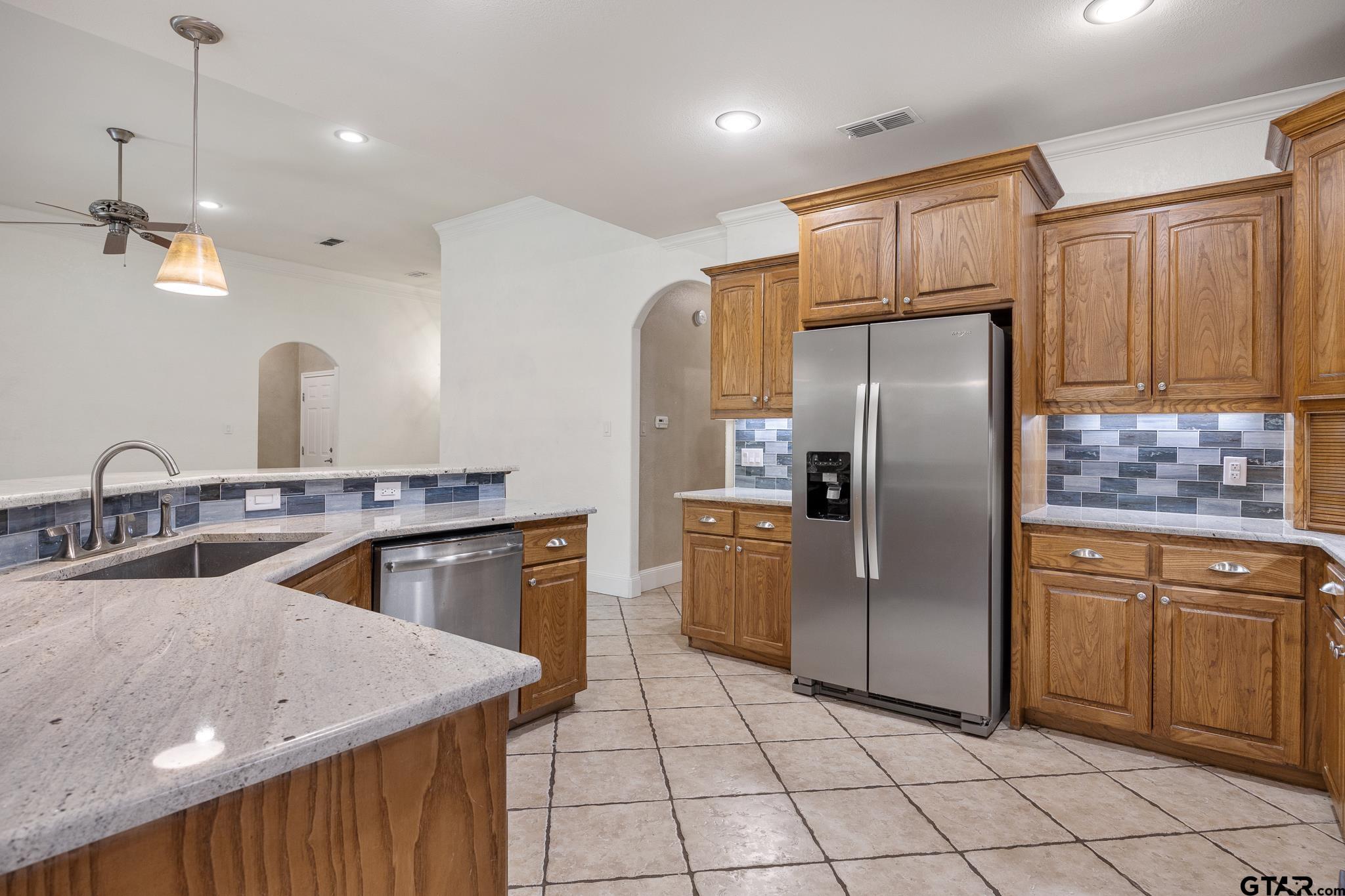 5603 Thomas Nelson Drive Tyler, TX 75707 - Photo 5 of 28 a kitchen with stainless steel appliances granite countertop a sink a stove a refrigerator a washer dryer and a dining table