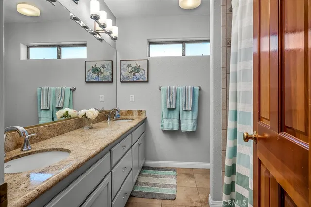 a bathroom with a granite countertop sink a mirror and shower