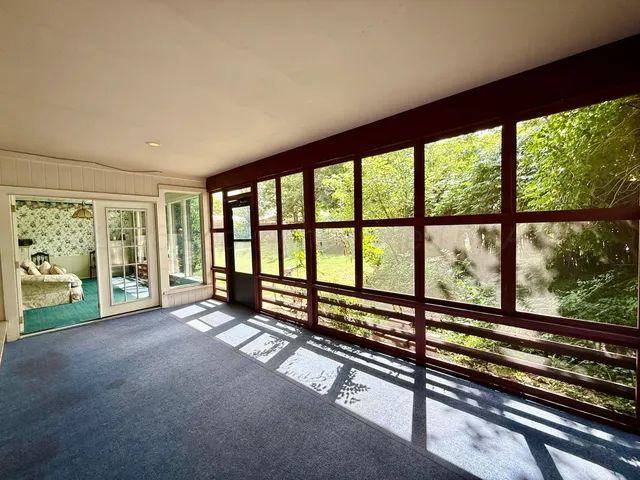 a view of an empty room with wooden floor and a floor to ceiling window