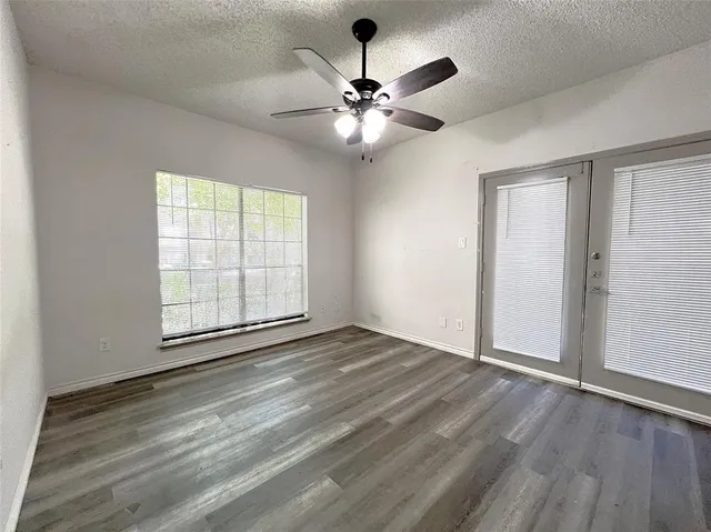 a view of an empty room with window and wooden floor