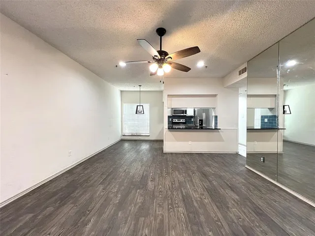 a view of an empty room with kitchen and window